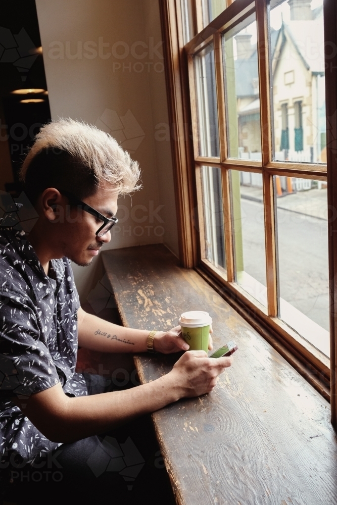 Asian man holding coffee cup and using mobile phone : Austockphoto Asian man holding coffee cup and using mobile phone - Australian Stock Image