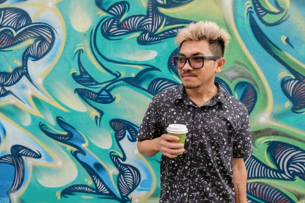 Asian man holding drink : Austockphoto Asian man holding drink - Australian Stock Image