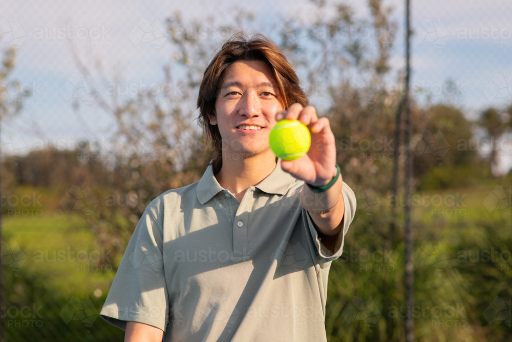 Image of asian man holding tennis ball - Austockphoto
