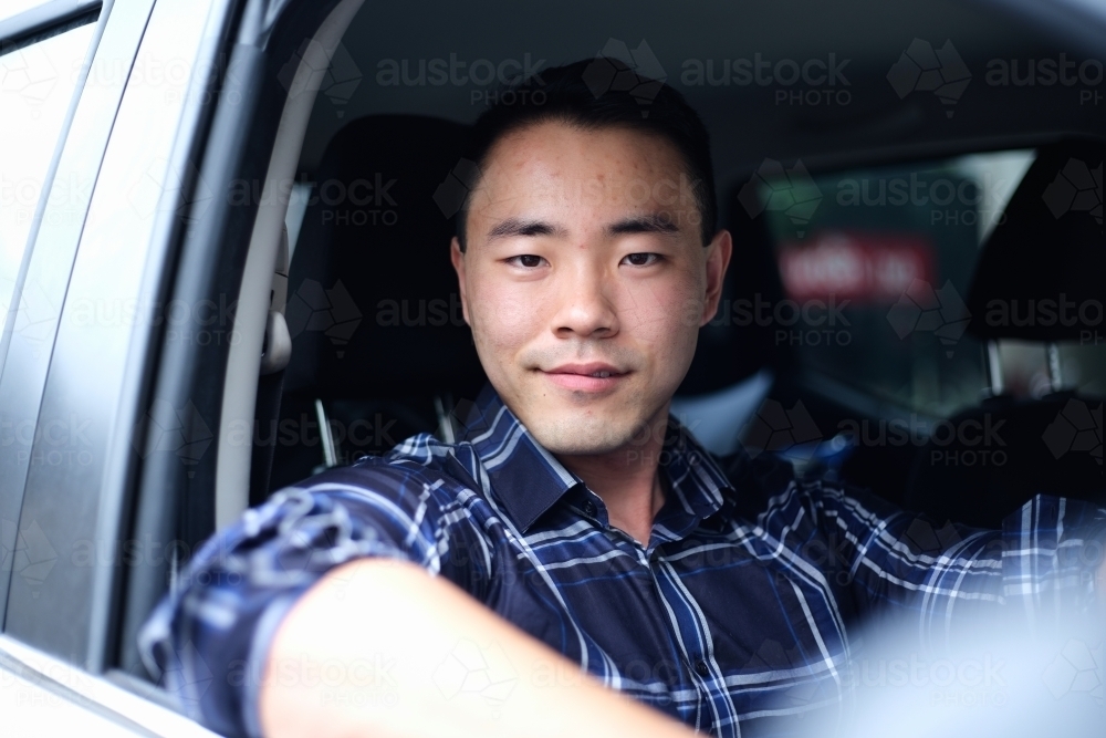 Asian man in driver's seat of car - Australian Stock Image