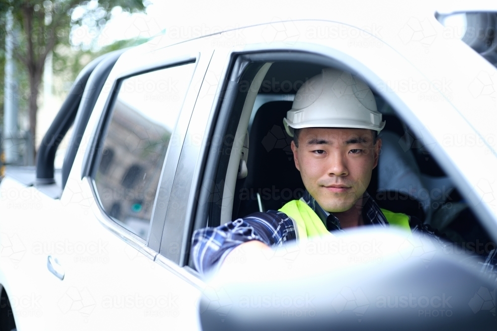 Asian man wearing hard hat in car - Australian Stock Image