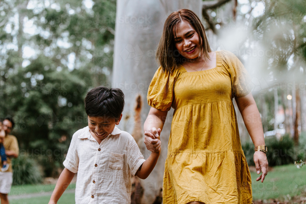 Asian mother and son holding hands walking at the park. - Australian Stock Image