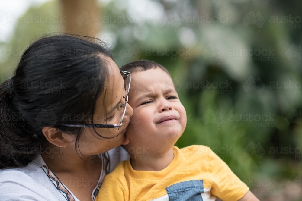 Asian mother comforts her crying 2 year old son - Australian Stock Image