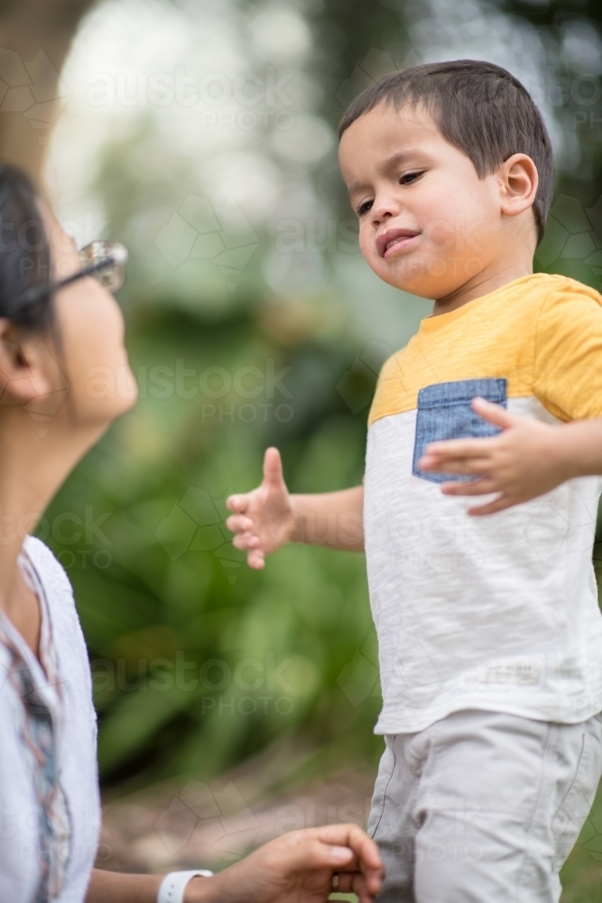 Asian mother comforts her crying 2 year old son - Australian Stock Image