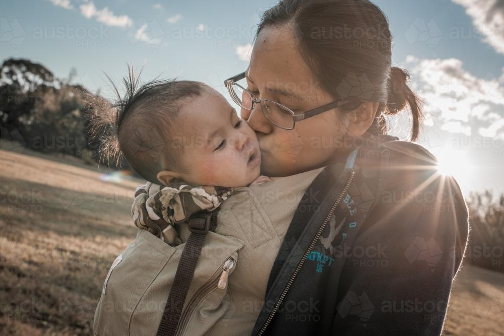 Asian mother walks with her mixed race baby in a Sydney suburban park - Australian Stock Image
