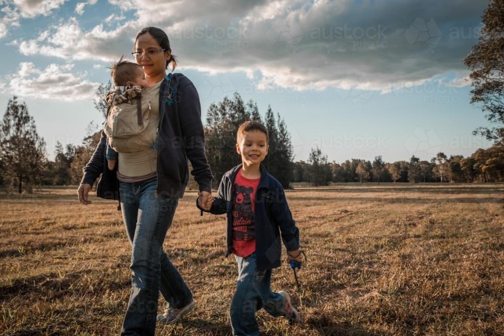 Asian mother walks with her mixed race boys in a Sydney suburban park - Australian Stock Image