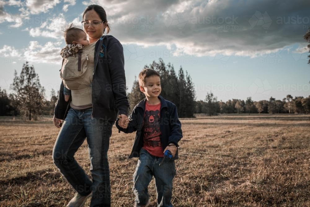 Asian mother walks with her mixed race boys in a Sydney suburban park - Australian Stock Image