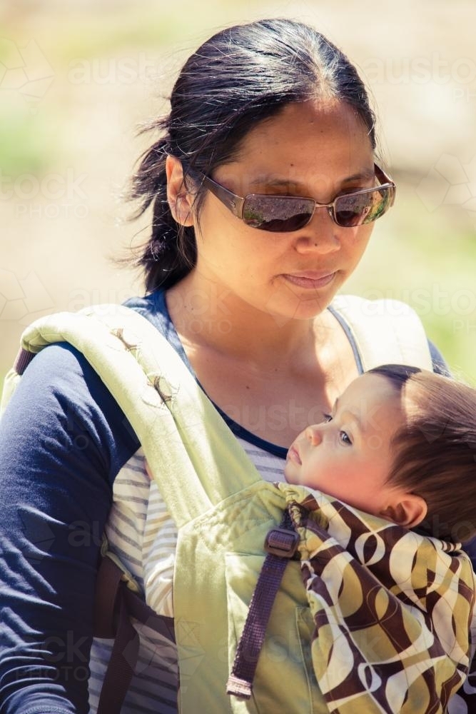 Asian mum outside walking in the summer sun with her mixed race baby boy - Australian Stock Image