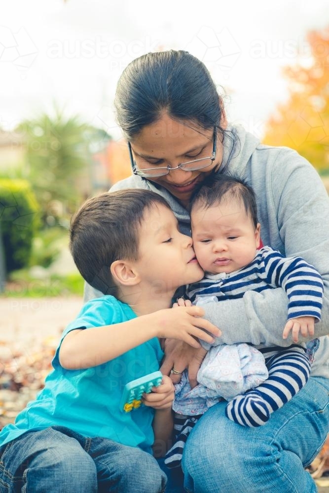 Asian mum with her mixed race boys in front of their suburban home - Australian Stock Image