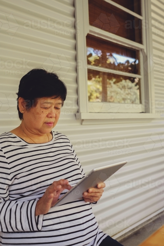 Asian senior woman using tablet - Australian Stock Image