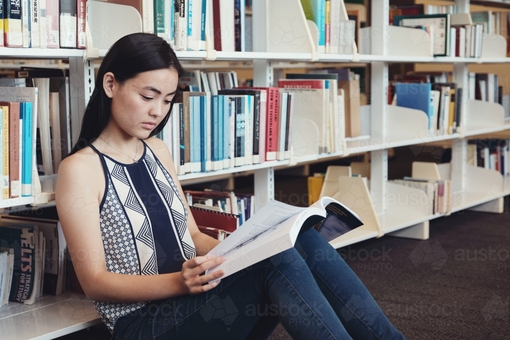 Asian students reading book in university library - Australian Stock Image