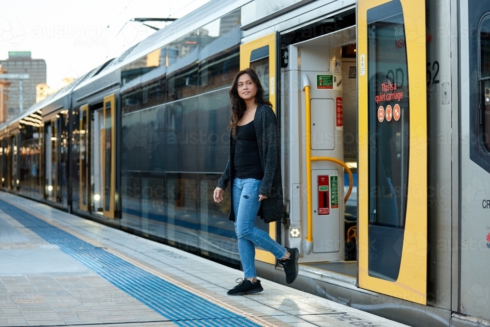 Asian woman getting off train at train station - Australian Stock Image