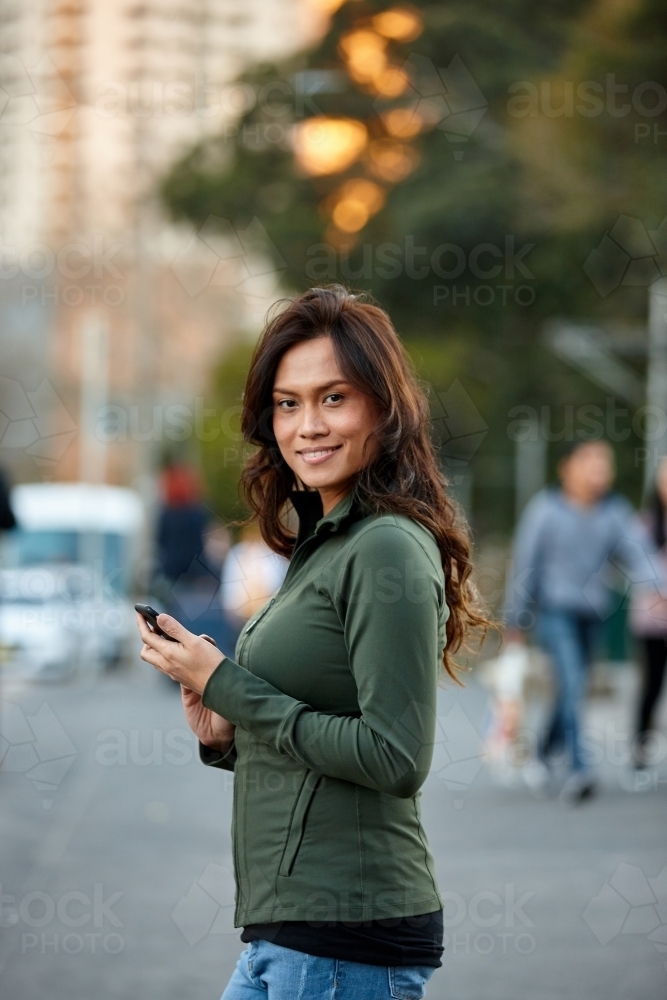 Asian woman hailing taxi with mobile phone - Australian Stock Image