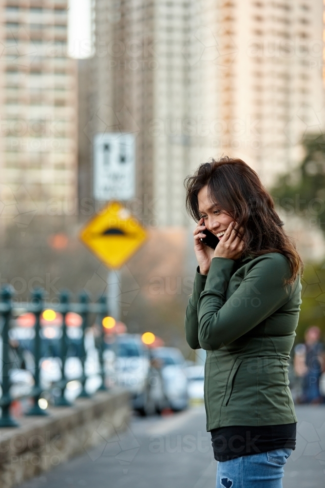 Asian woman hailing taxi with mobile phone - Australian Stock Image