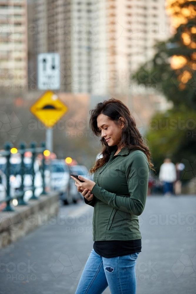 Asian woman hailing taxi with mobile phone - Australian Stock Image