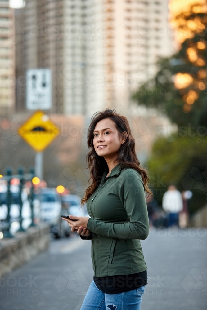 Asian woman hailing taxi with mobile phone - Australian Stock Image