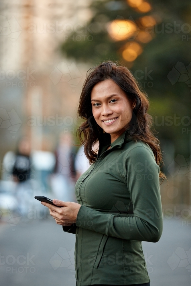 Asian woman holding mobile phone - Australian Stock Image