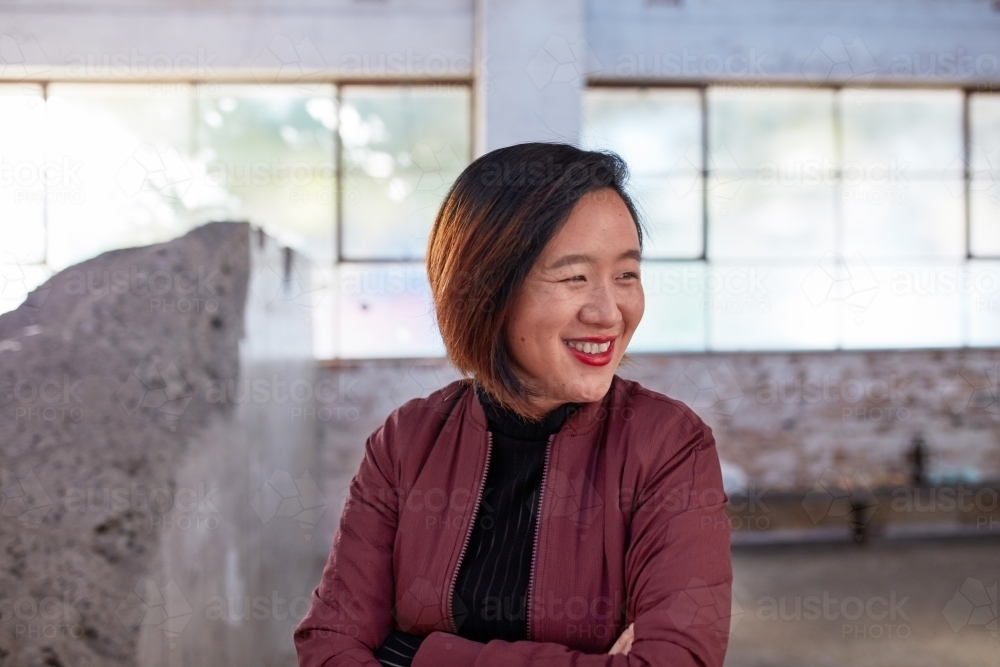 Asian woman laughing in studio warehouse - Australian Stock Image