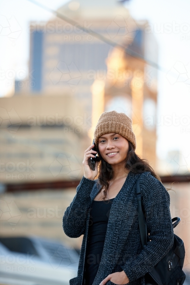 Asian woman talking on phone waiting at train station - Australian Stock Image