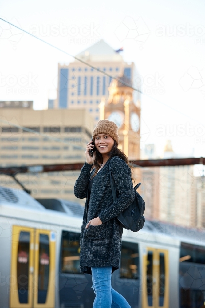 Asian woman talking on phone waiting at train station - Australian Stock Image