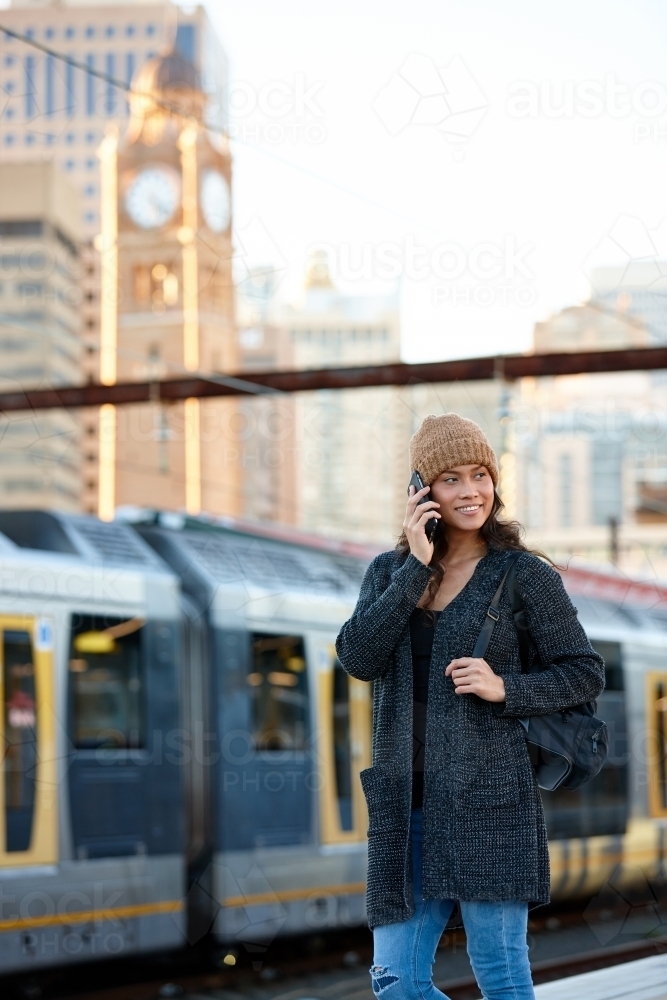 Asian woman waiting at train station with mobile phone - Australian Stock Image