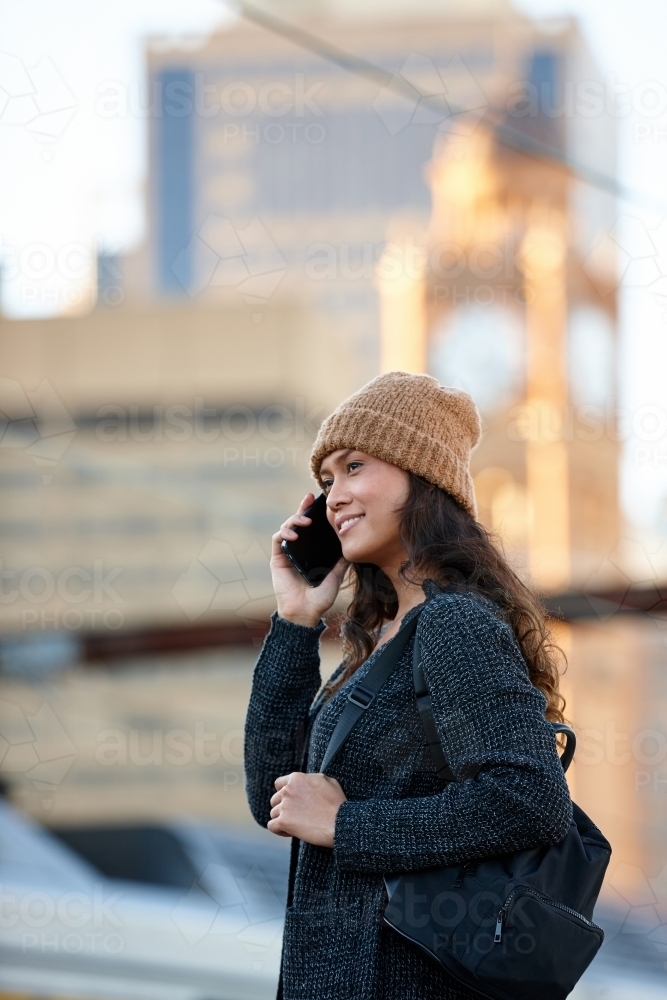 Asian woman waiting at train station with mobile phone - Australian Stock Image
