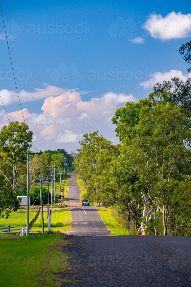 Asphalt country road (Schilling Road, Calliope) with telephone poles - Australian Stock Image