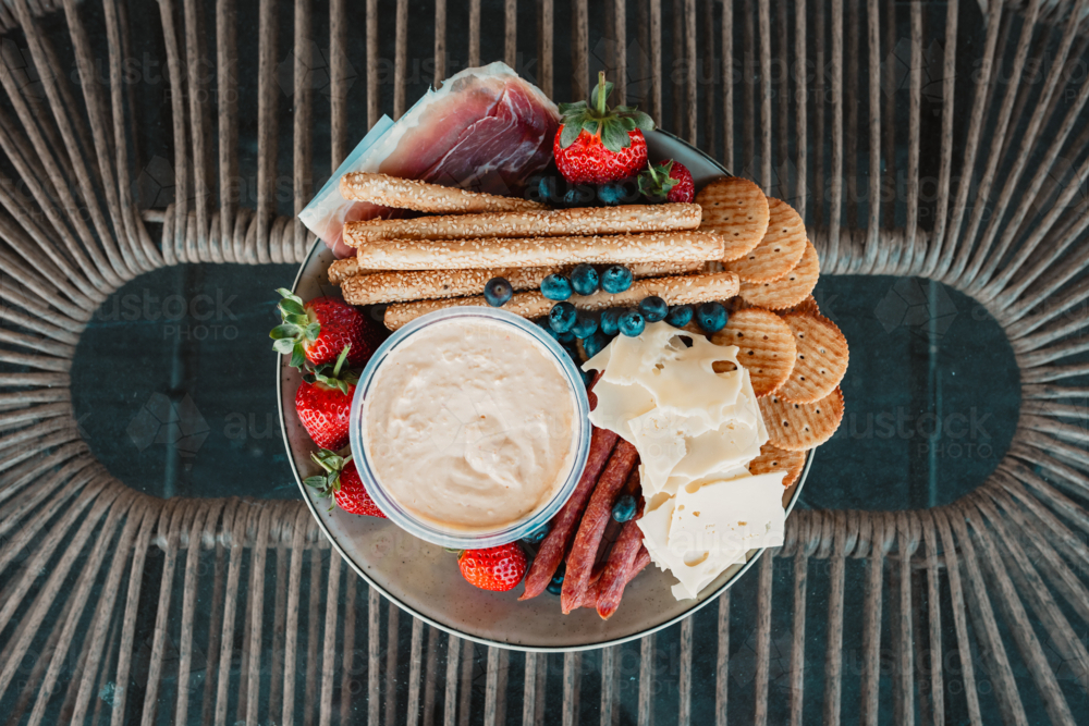 Assorted cheeses, meats, and fruits on a platter for a gourmet snack. - Australian Stock Image
