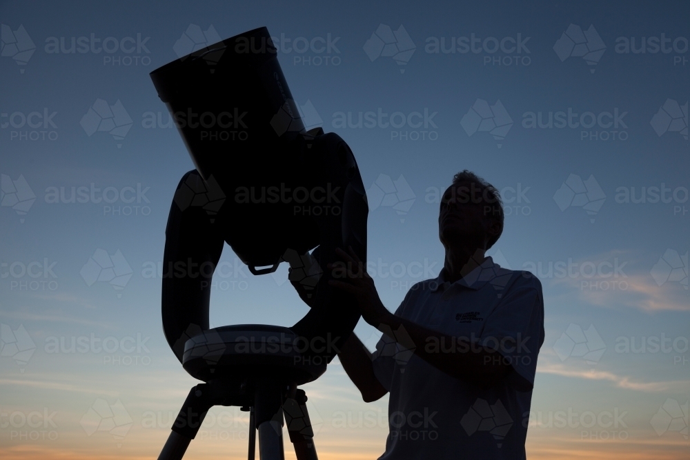Astronomer with telescope in silhouette - Australian Stock Image