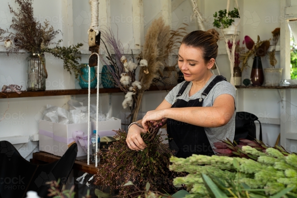 Attractive female florist preparing flowers for an event - Australian Stock Image