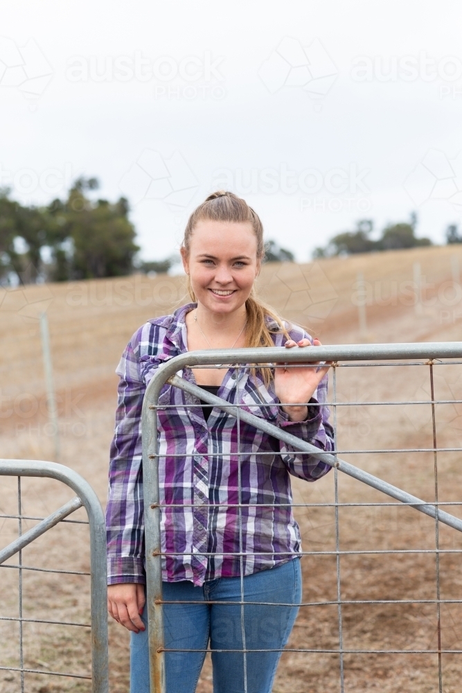 Attractive young woman at farm gate - Australian Stock Image
