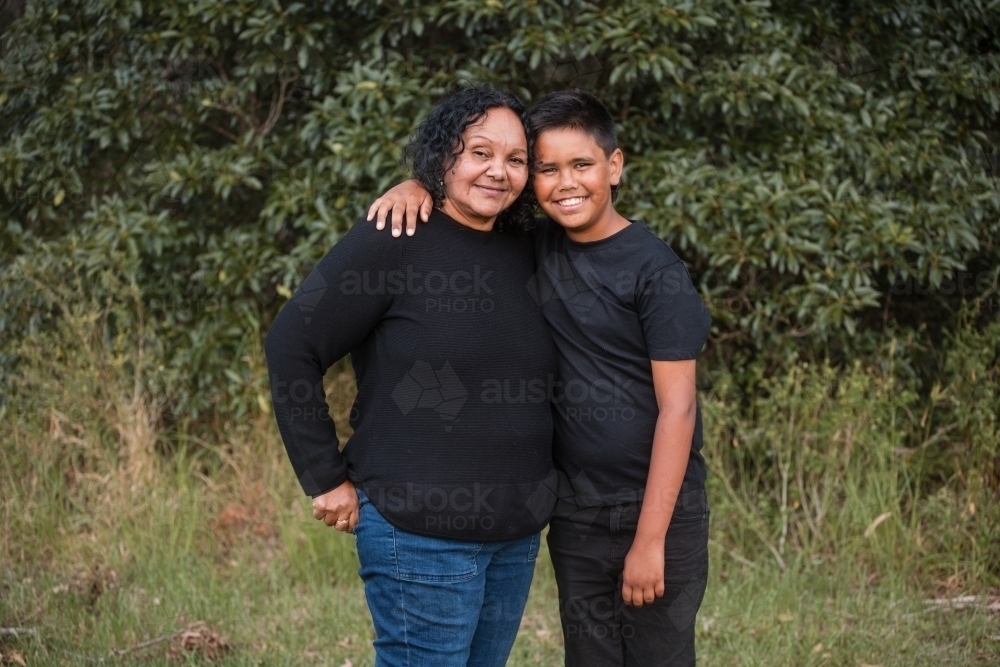 Aunty woman standing smiling outside amongst the trees - Australian Stock Image