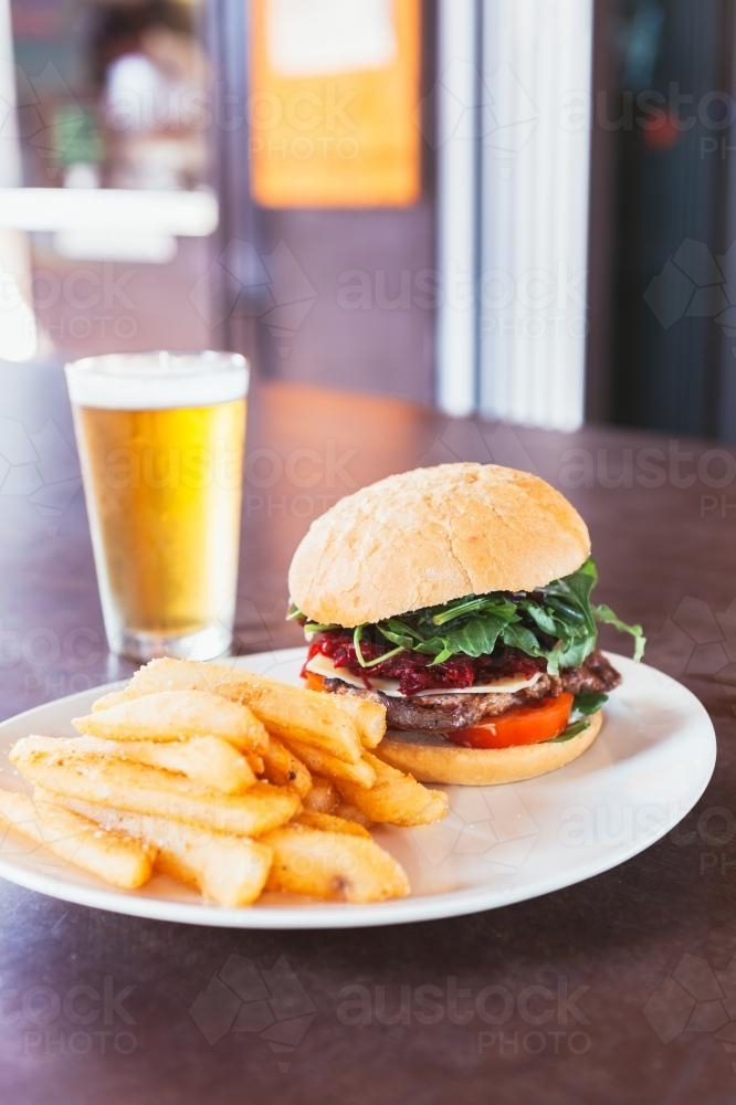 aussie burger with beetroot on plate with chips and a beer - Australian Stock Image