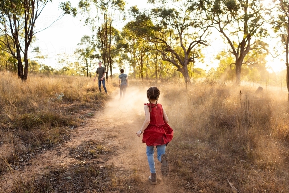 Aussie country kids running through dusty paddock in rural Australia - Australian Stock Image
