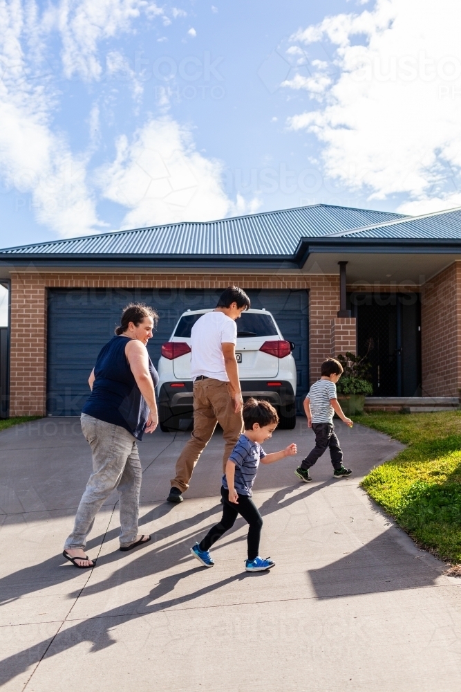Aussie family walking home together in afternoon sunlight - Australian Stock Image