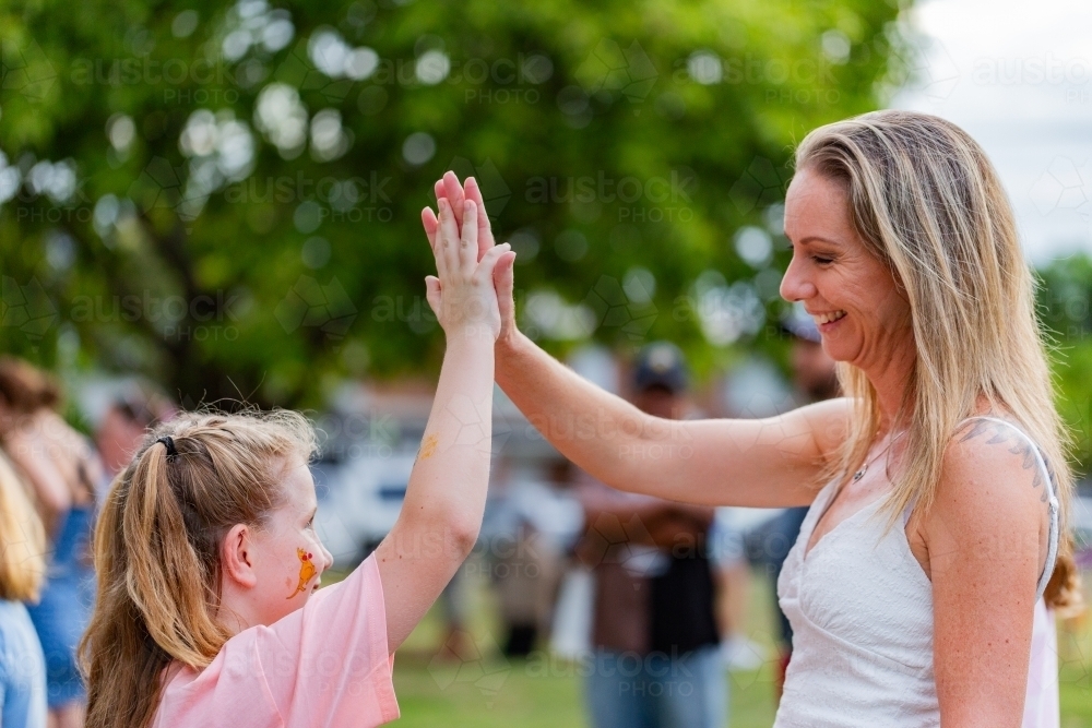 Aussie girl giving her mum a high five at community event - Australian Stock Image