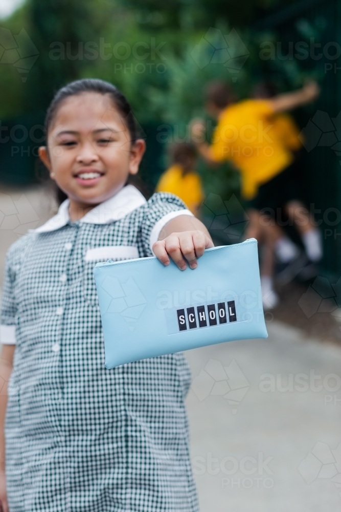 Image of Aussie kid of Filipino ethnicity holding out a pencil case