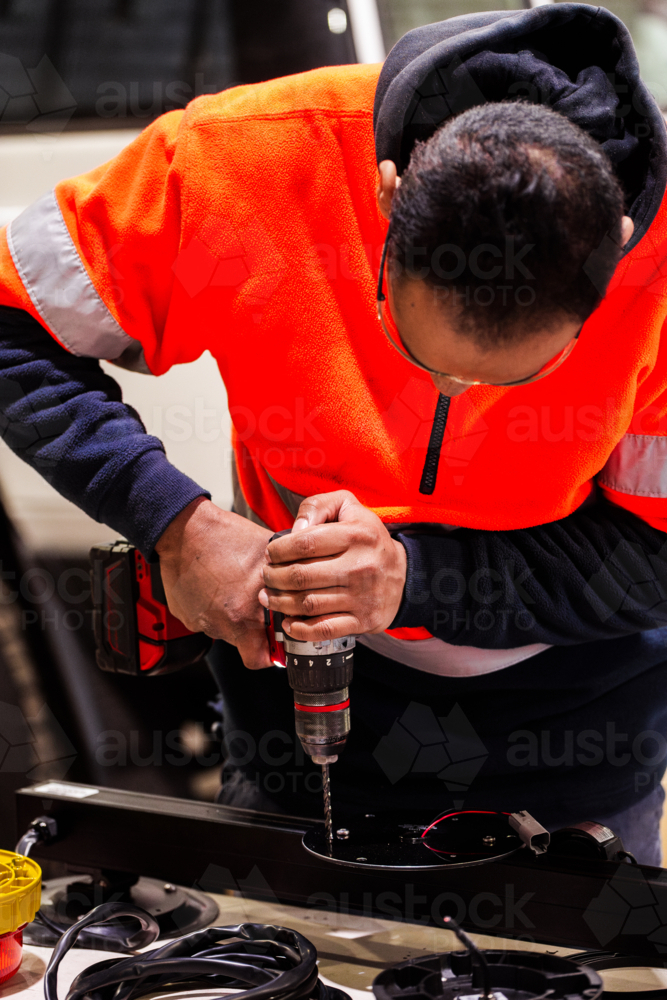 Aussie male mechanic drilling on vehicles light bar for installation - Australian Stock Image