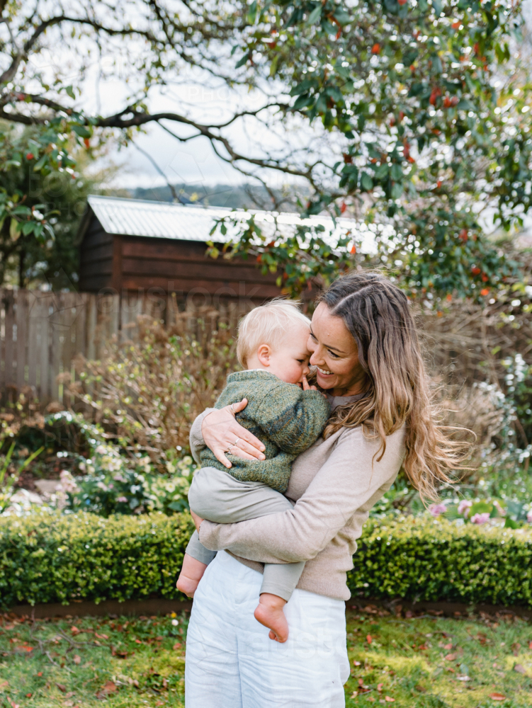 Aussie mum carrying toddler son in the garden - Australian Stock Image