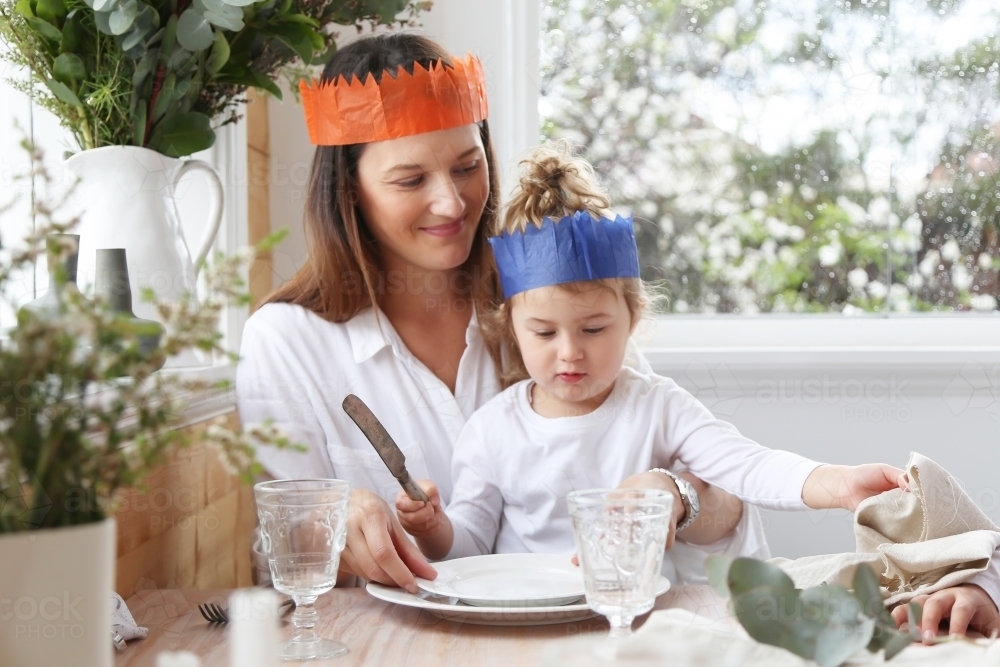 Mother and daughter at table wearing Christmas hats - Australian Stock Image
