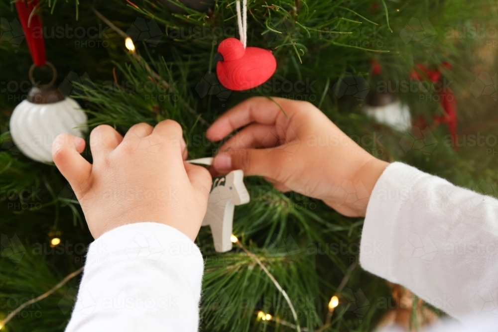 Close up of little hands decorating Christmas tree - Australian Stock Image