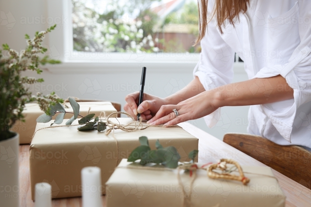Close up of hands writing gift tag on present - Australian Stock Image