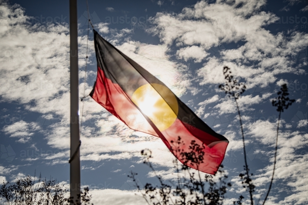 Australian Aboriginal Flag flying in the wind in bright sunshine - Australian Stock Image