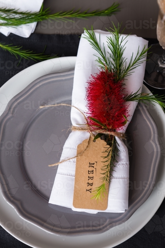 Australian Christmas table place setting with a bottlebrush flower and tag reading "merry" - Australian Stock Image