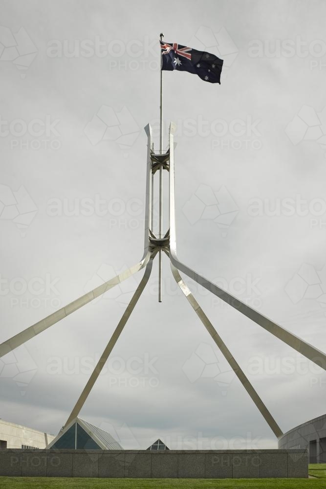 Australian Flag flying at Parliament House on an overcast day - Australian Stock Image