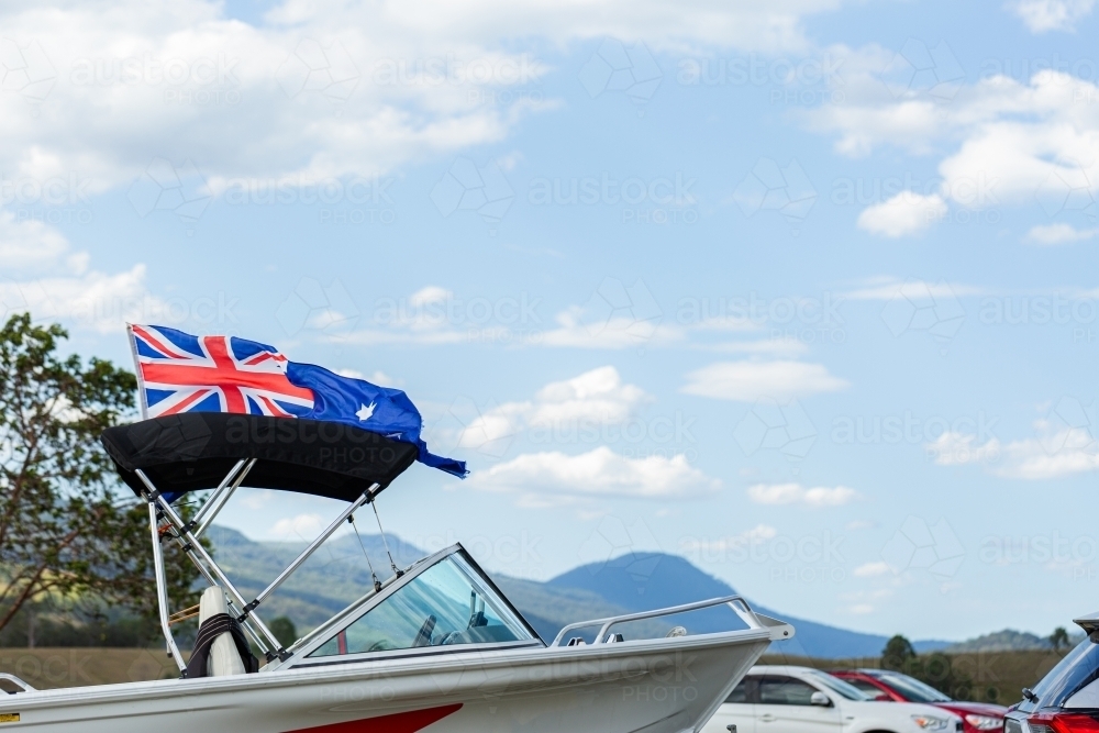 Australian flag flying from boat in lakeside campground - Australian Stock Image