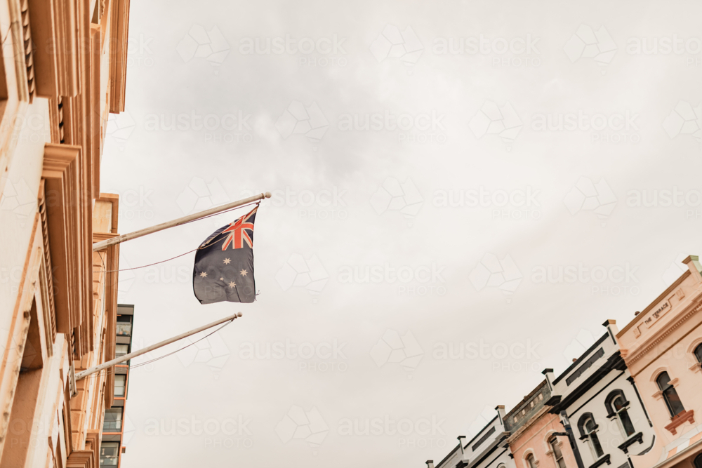 Australian flag flying in Newcastle street with terrace houses in background - Australian Stock Image