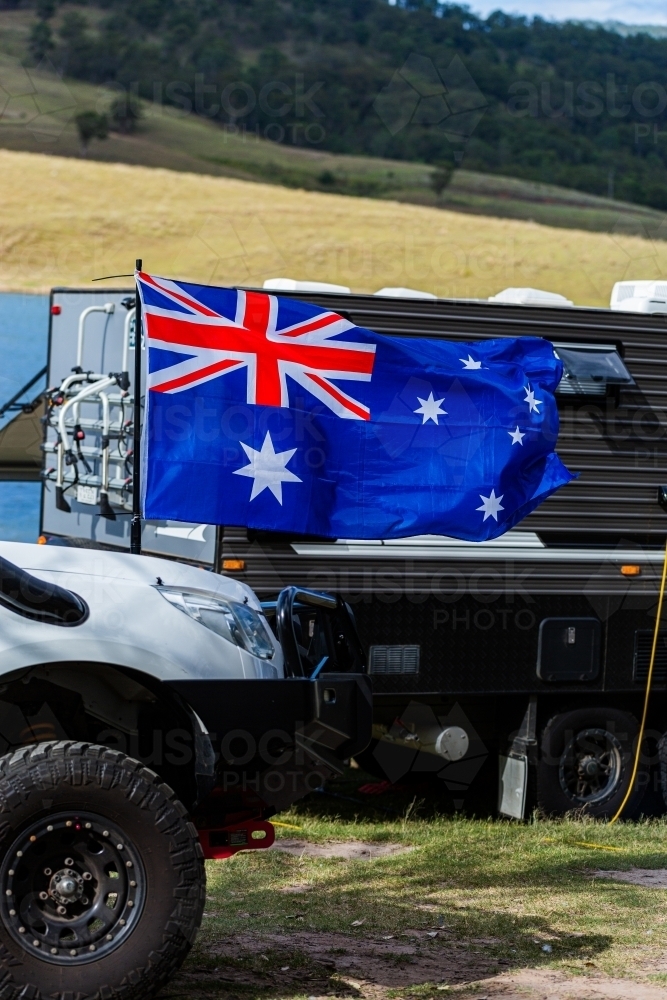 Australian flag flying in wind at lakeside campground on Australia Day - Australian Stock Image