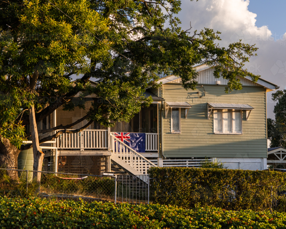 Australian flag hangs proudly on the veranda railing of an old timber house - Australian Stock Image
