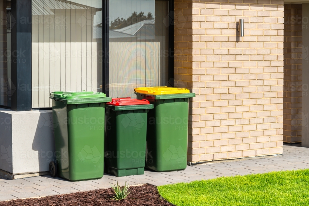 Australian garbage wheelie bins with colourful lids for recycling, general and green waste provided - Australian Stock Image